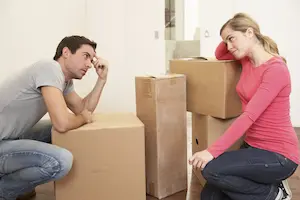 Man and woman sitting by packed boxes