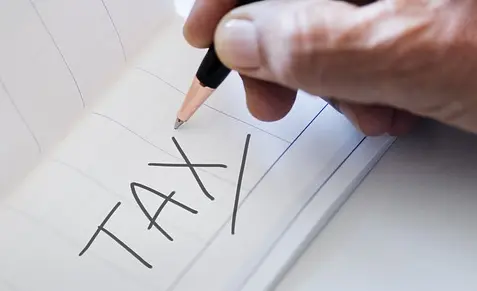 Pen in hand writing tax on paper